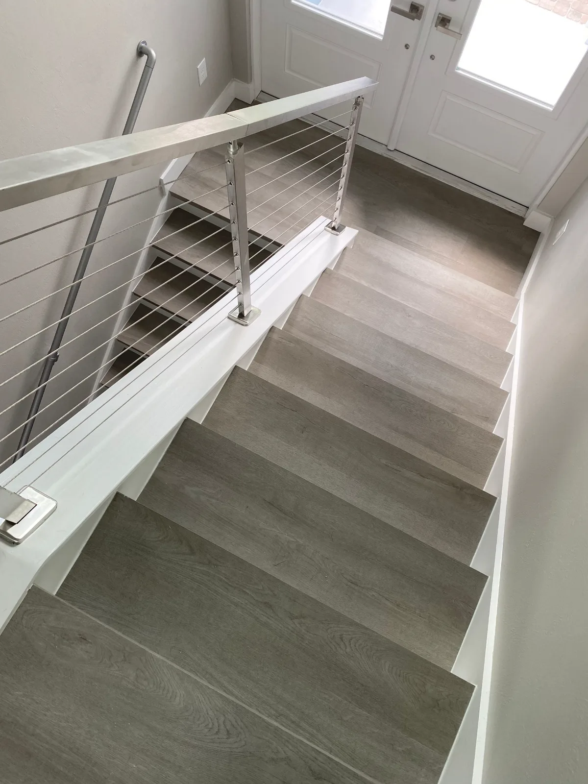 Luxury vinyl plank stairs with cable railing at an entry landing