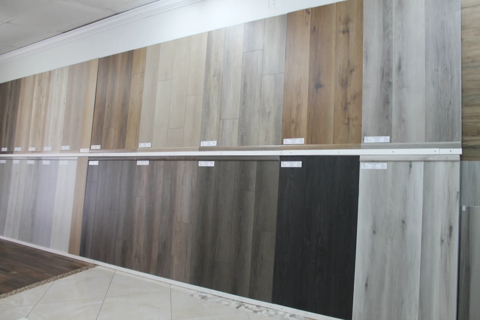 Wall of full-length Style SPC plank samples in oak, greige, grey and walnut at the Fort Myers showroom