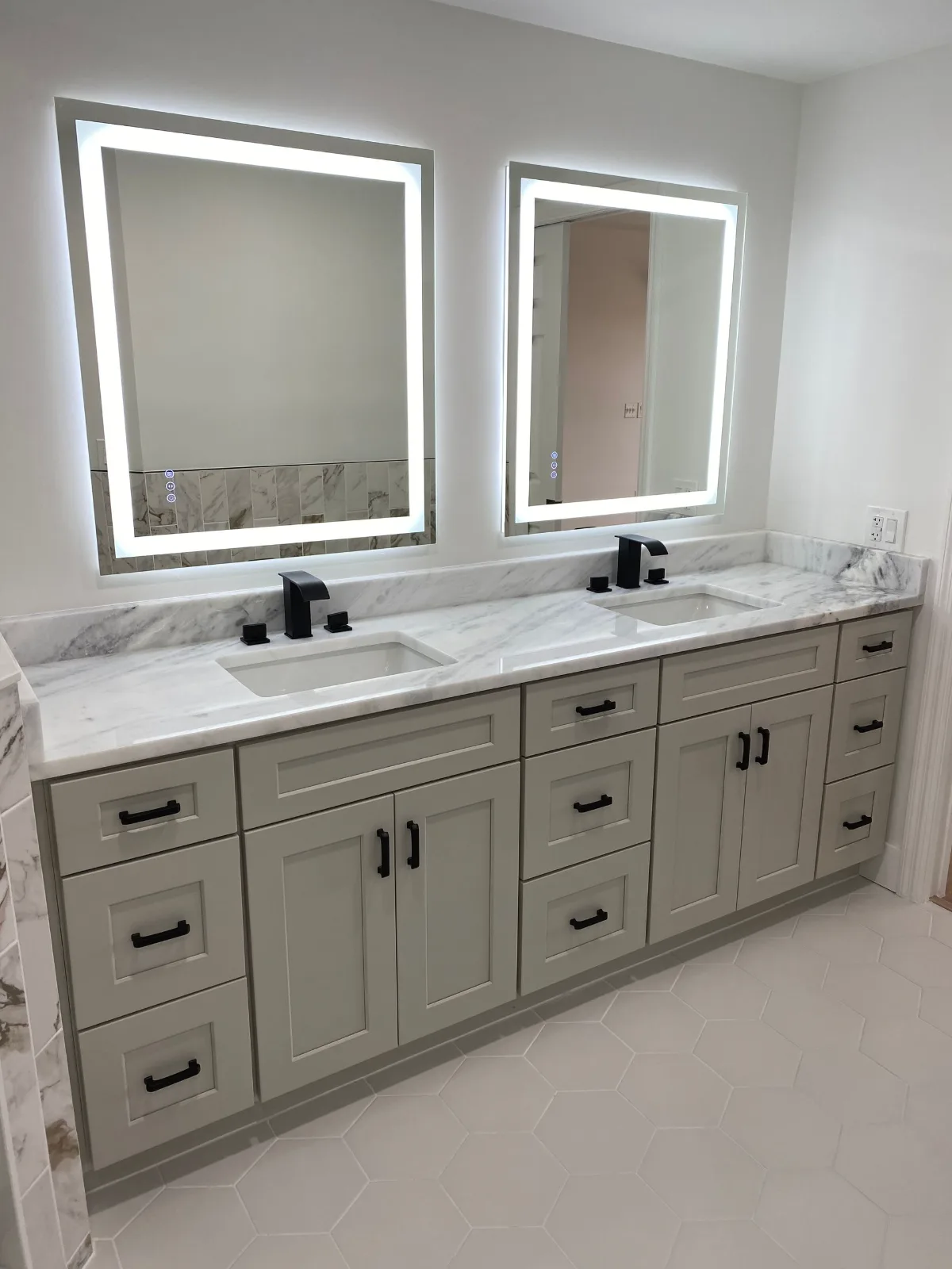 Master bathroom vanity in marble-look surfaces with backlit mirrors